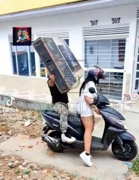 Se vuelve viral pareja que transporta una pantalla en una moto y termina cayendose